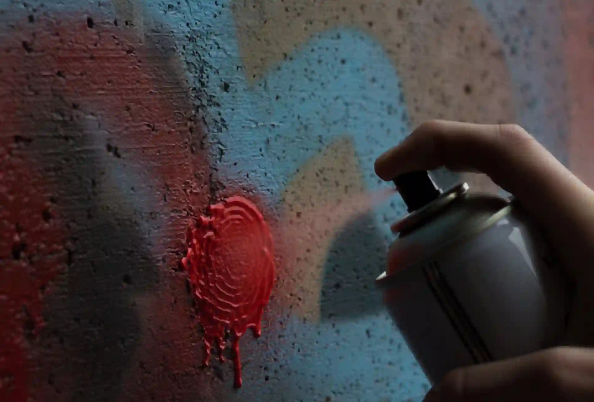 Spray can spraying graffiti on wall